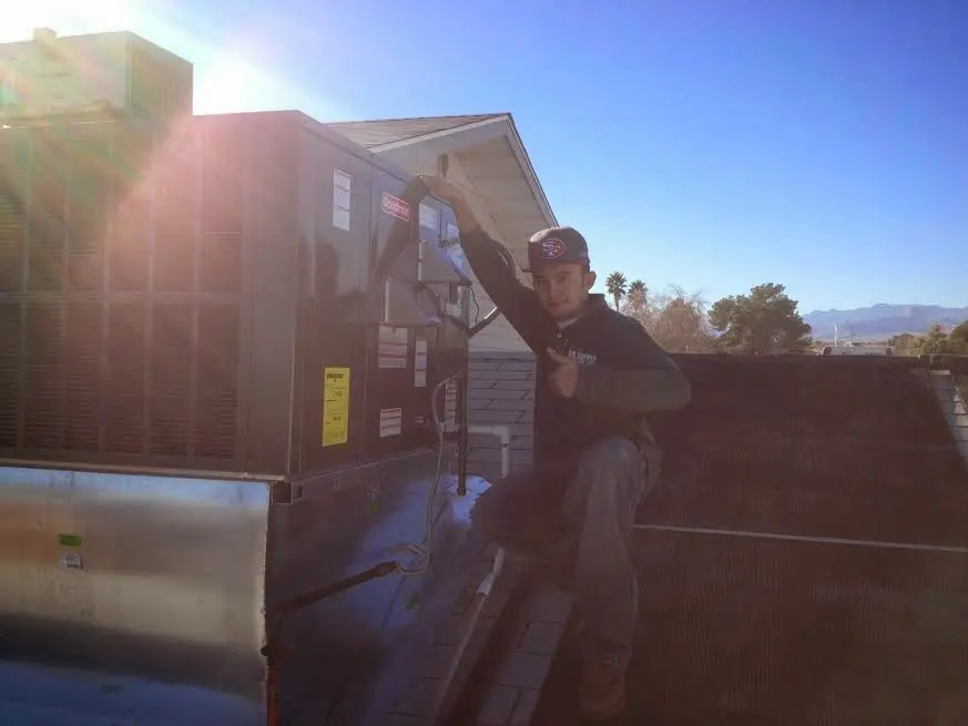 HVAC technician performing HVAC Inspection on a rooftop unit in Brock Hall